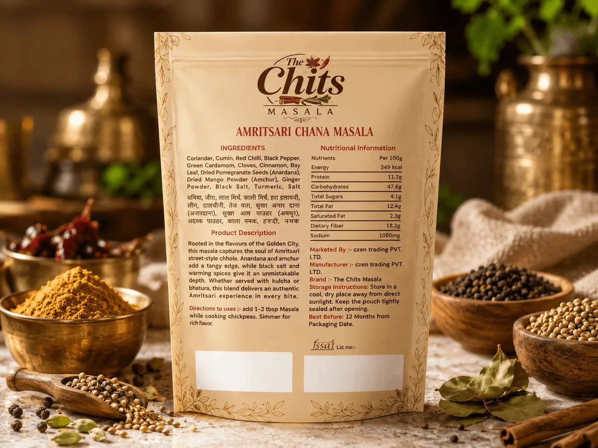 A package of Chits Masala Amritsari Ghana Masala spice blend stands upright in a rustic setting, surrounded by bowls of whole spices, cinnamon sticks, and green leaves on a wooden surface.