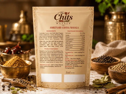 A package of Chits Masala Amritsari Ghana Masala spice blend stands upright in a rustic setting, surrounded by bowls of whole spices, cinnamon sticks, and green leaves on a wooden surface.