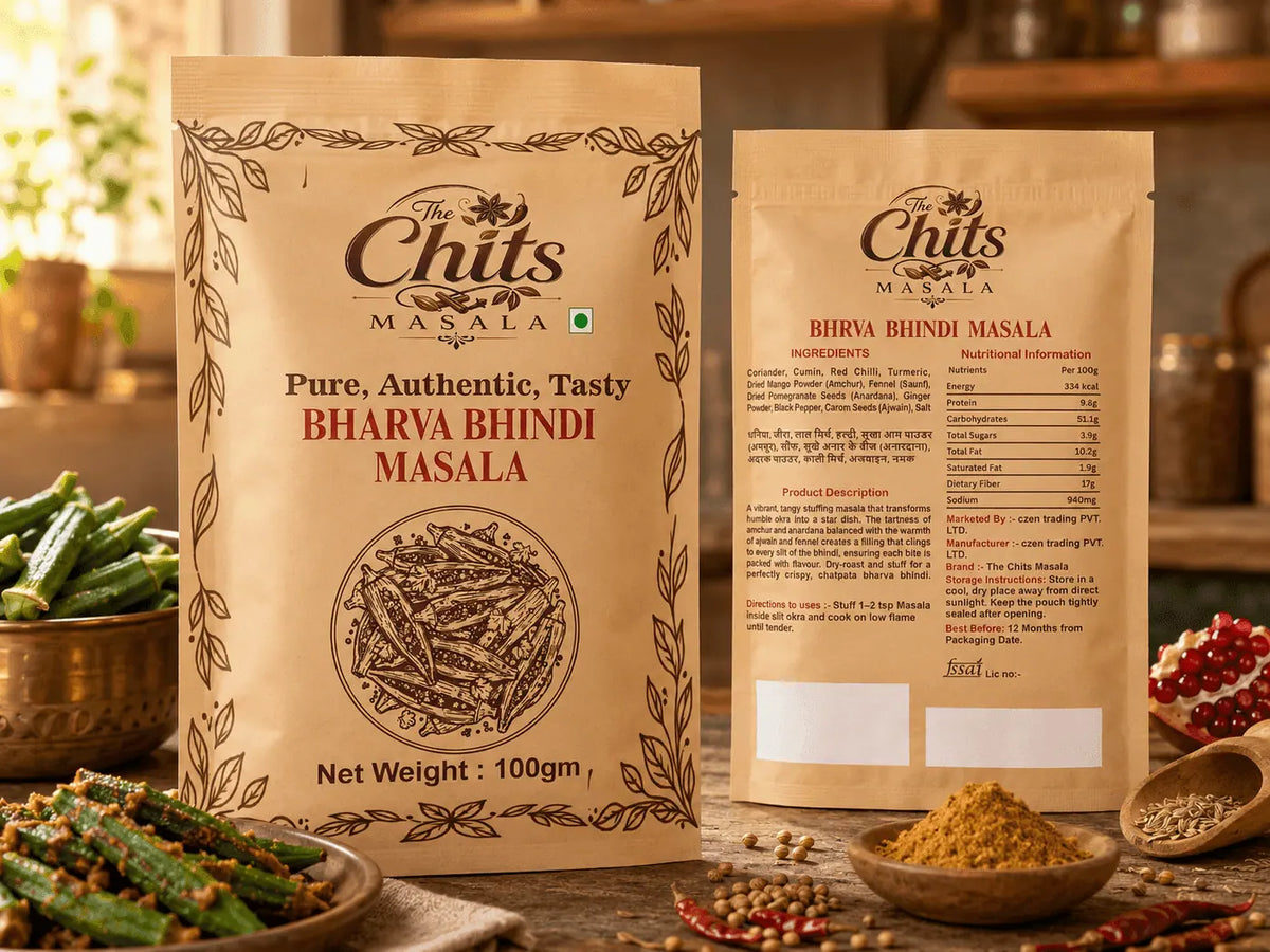Two stand-up pouches of Chits Masala Bharya Bhindi Masala spice blend displayed on a rustic wooden table with bowls of ingredients like green beans, red chilies, and pomegranate seeds in the background.