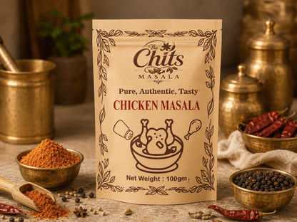 A 100g pouch of 'The Chits' Masala Chicken Masala spice mix, displayed in a rustic kitchen setting with brass bowls of spices, dried red chilies, and peppercorns.
