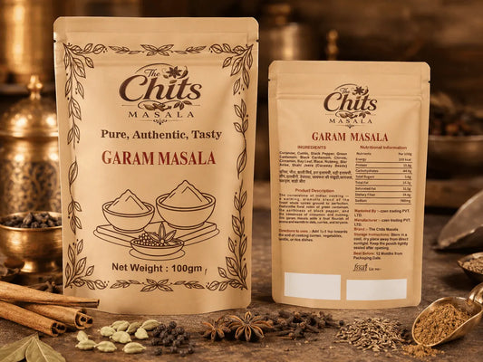Two stand-up pouches of The Chits Masala Garam Masala spice mix displayed on a rustic wooden surface with cinnamon sticks, cardamom pods, and whole spices in the background.