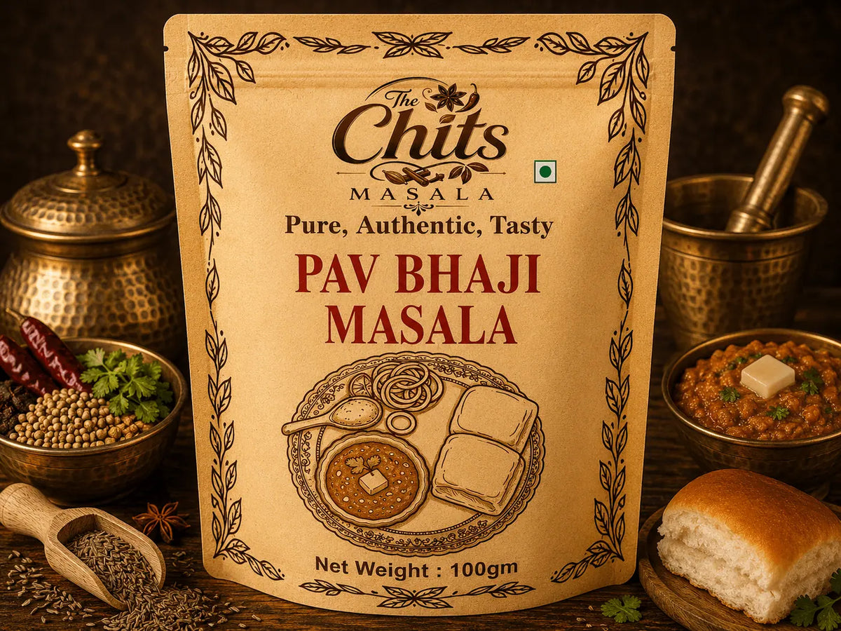 A 100g stand-up pouch of The Chits Masala Pav Bhaji Masala centered on a dark rustic background, surrounded by ingredients and prepared food including brass vessels, spices, a bowl of pav bhaji, and a bread roll.
