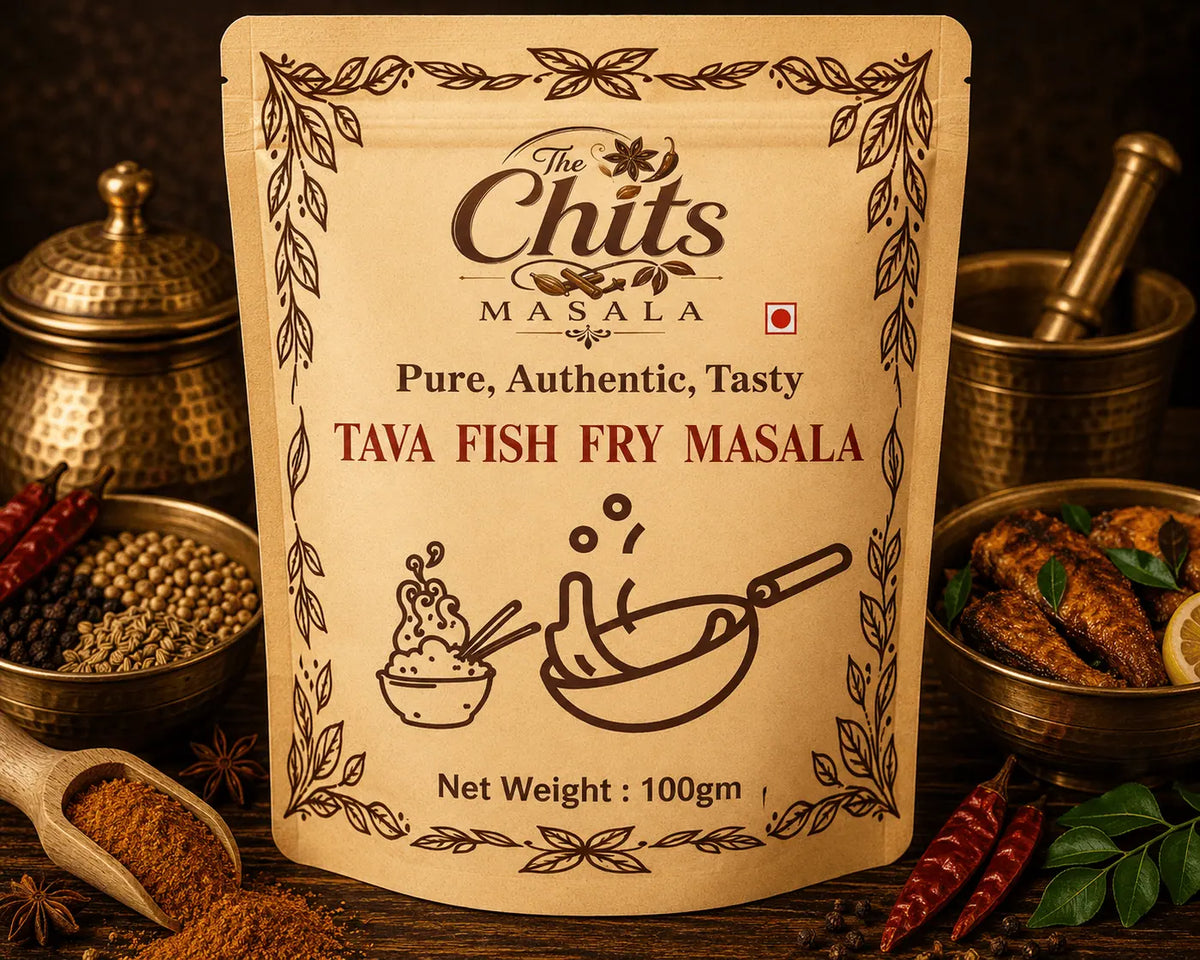 A stand-up pouch of The Chits Masala Tava Fish Fry Masala spice mix, displayed on a rustic wooden table surrounded by ingredients like whole spices, red chilies, and cooked fish in brass vessels.